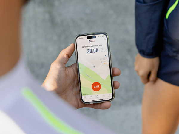 Bėgime dalyvaujantis dalyvis telefone žiūri, kada prasidės bėgimas.